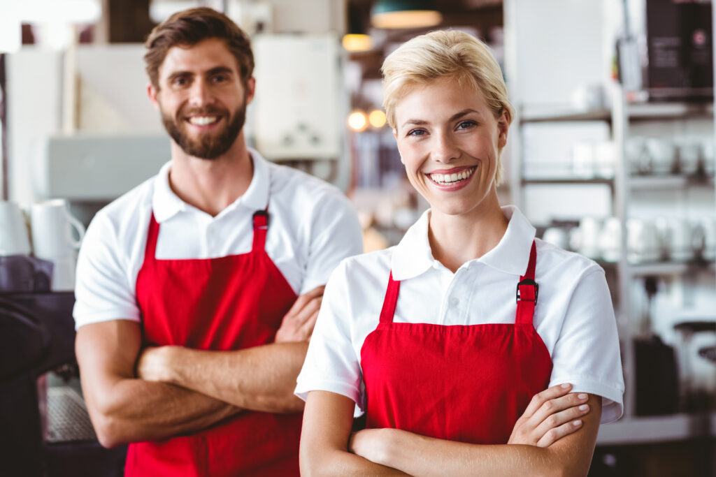 Two baristas smiling at the camera at the cafe